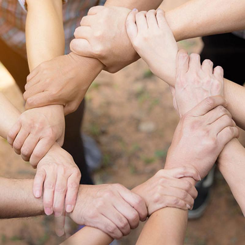 Group of hands holding at the wrist and forming a circle.