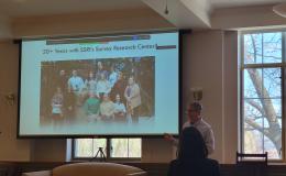 Dave Almeida, a white man in white shirt and brown pants, presents about working with SSRI's Survey Research Center.