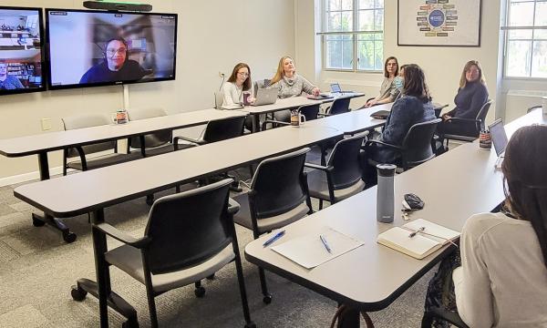 Wide shot of the Henderson conference room with Open House attendees.