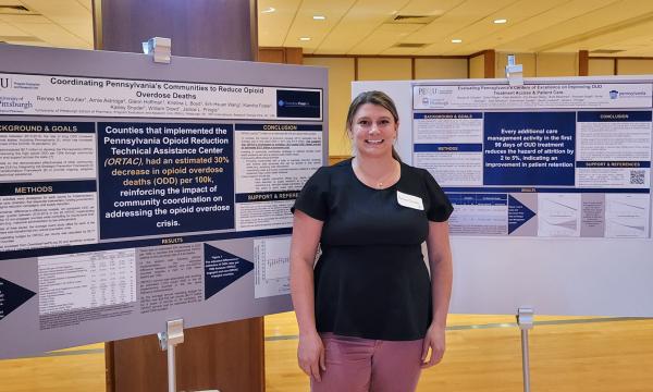 Renee Cloutier poses next to two posters she submitted for the poster session.