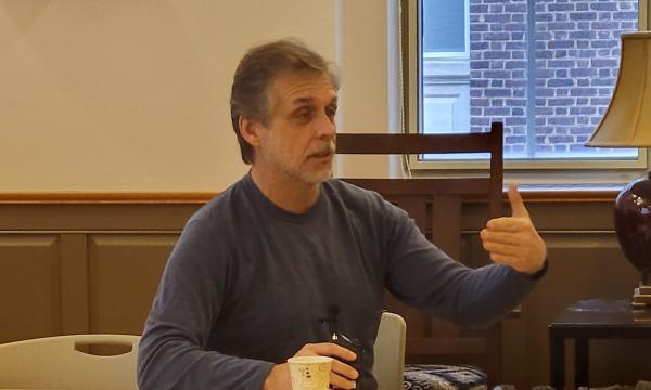 Marty Sliwinski, a white man with grey hair in a blue sweater, talks to the group of attendees.