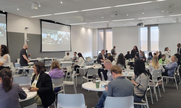 A wideshot of the room with CSUA Conference attendees chatting and mingling during one of the breaks.
