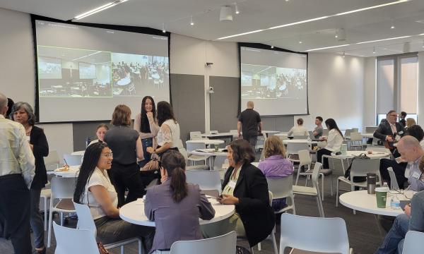 A second wideshot of the room with CSUA Conference attendees chatting and mingling during one of the breaks.