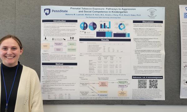 Student stands next to her poster.