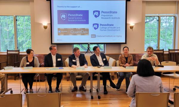 Group of panelists sits at the front for a discussion about research and collaboration.