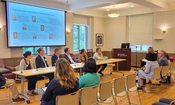 Group of panelists sits at the front for a discussion about research and collaboration.