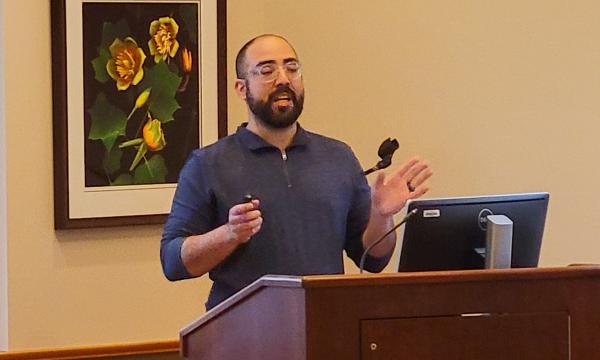 Nelson Roque, a white man wearing a blue shirt with a beard, presents to the group.