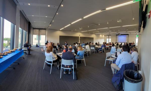 Wideshot of the conference attendees sitting down at round tables.